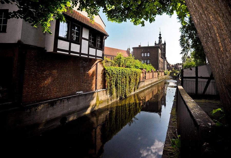 ein Kanal in einer Stadt mit einem Gebäude und einer Kirche in der Unterkunft World Hostel - Old Town in Danzig