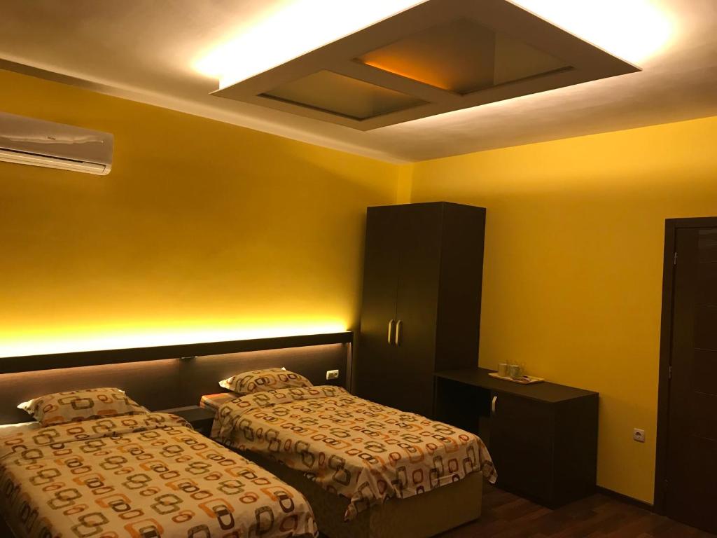 two beds in a hotel room with yellow walls at Център in Pleven