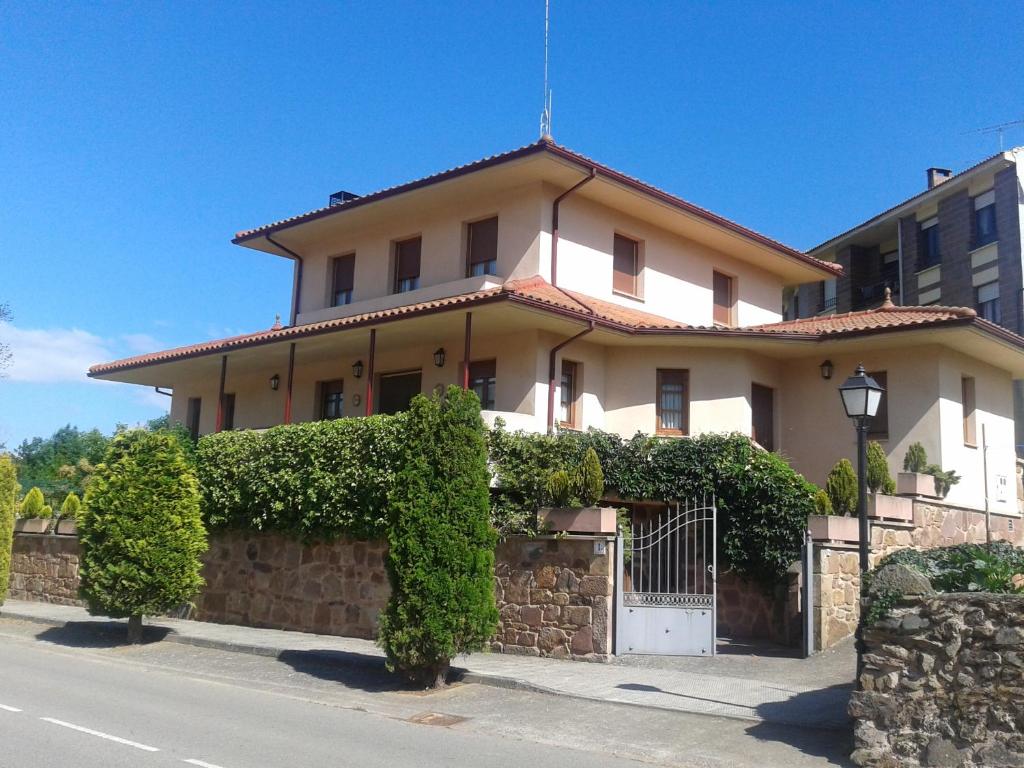 une grande maison blanche avec une clôture et des buissons dans l'établissement Tres Fuentes Turismo, à Valgañón