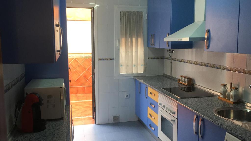 una pequeña cocina con armarios azules y fregadero en Casa hurtado, en Coria del Río