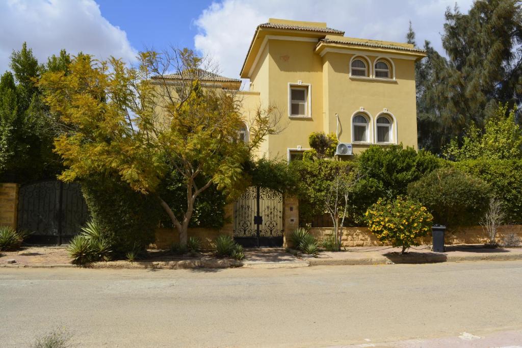 a yellow house with a fence in front of it at Villa in Golf Al-Solaimaneyah in 6th Of October