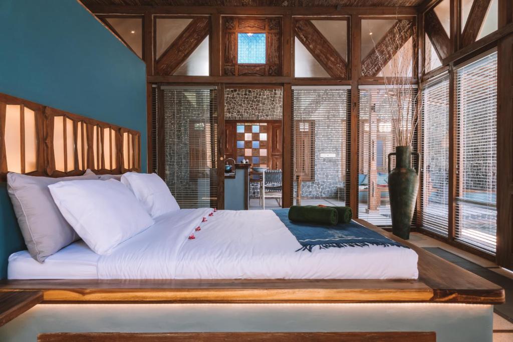 ein Schlafzimmer mit einem großen Bett in einem Zimmer mit Fenstern in der Unterkunft Samsara Villas in Gili Air