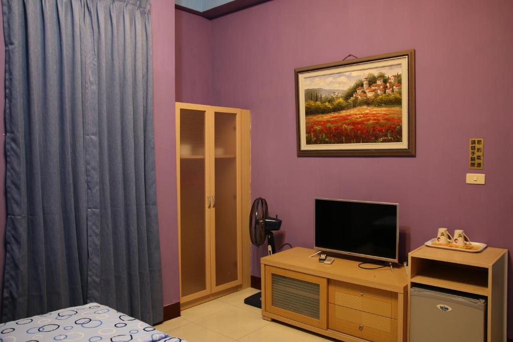 a room with a bedroom with purple walls and a television at The Beauty of Basalt B&amp;B in Magong