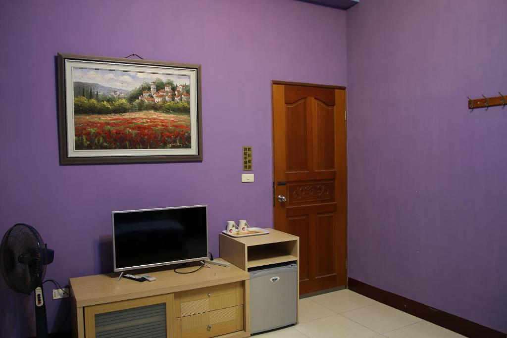 a room with a purple wall with a television and a painting at The Beauty of Basalt B&amp;B in Magong