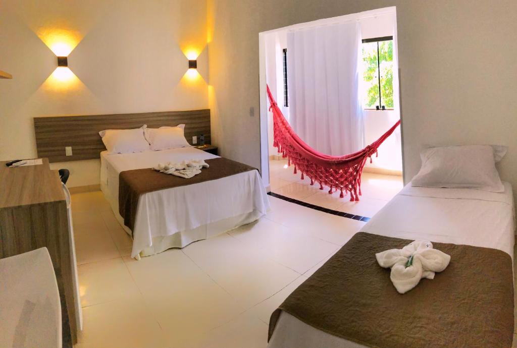 a hotel room with two beds and a window at Pousada Paraíso Maragogi in Maragogi