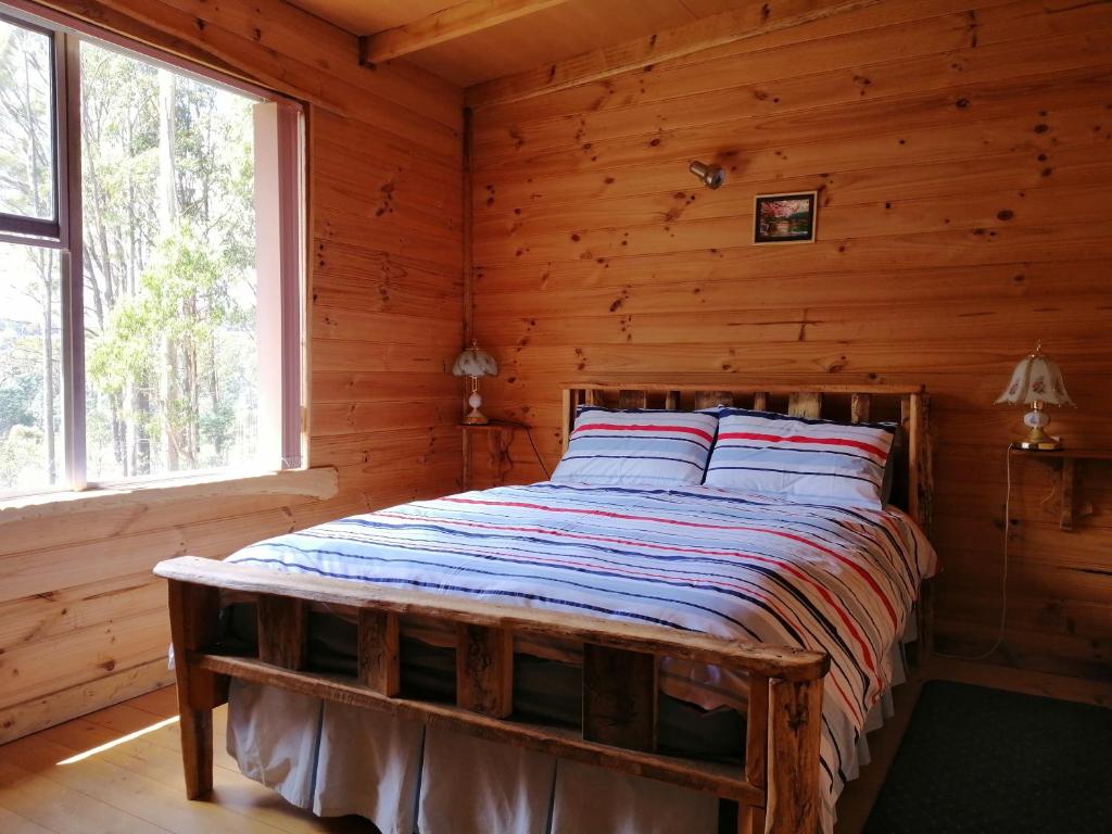 um quarto com uma cama num chalé de madeira em Minnow cabins Lower Beulah em Sheffield