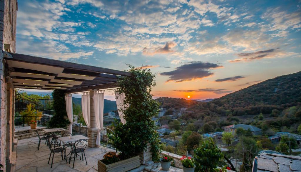 a patio with a table and chairs and a sunset at Pirrion Wellness Boutique Hotel in Ano Pedina