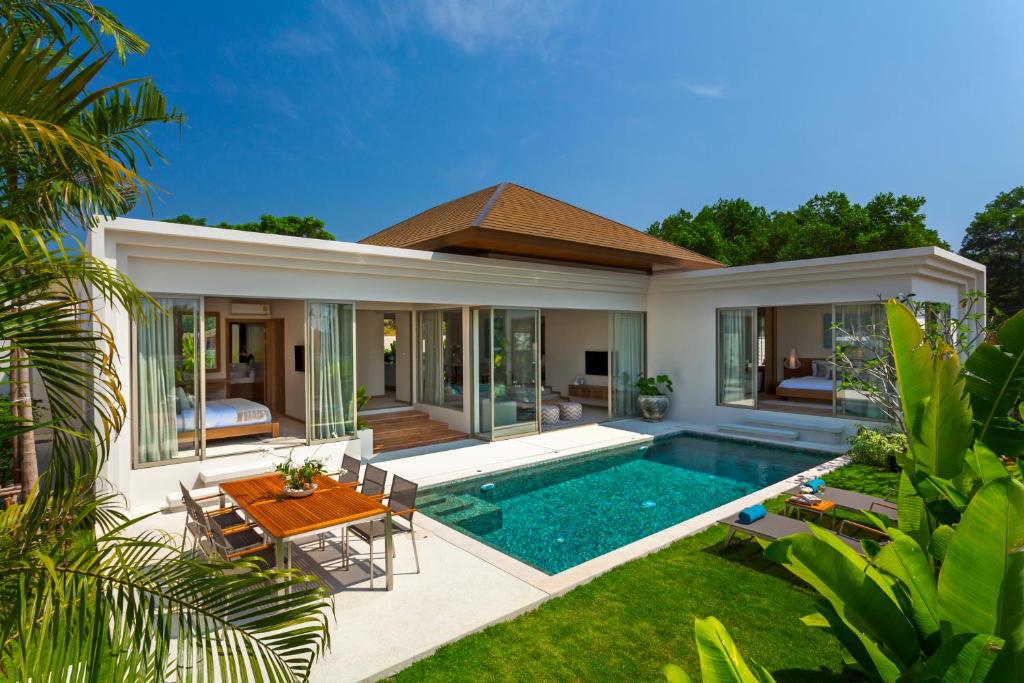 a villa with a swimming pool in front of a house at Trichada Villas in Bang Tao Beach