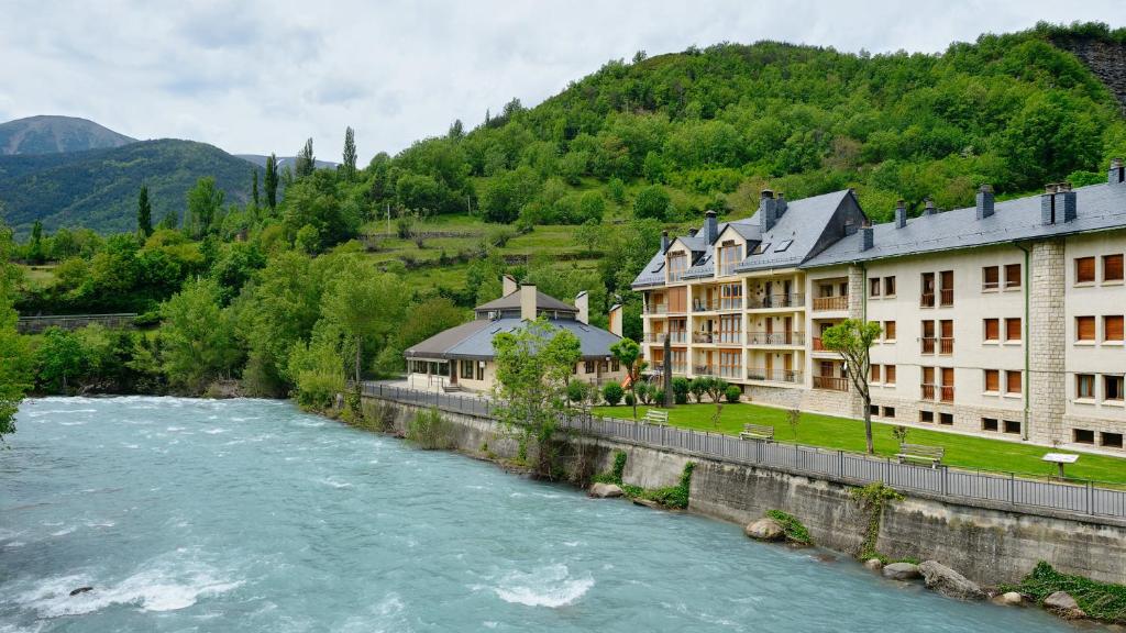 a river in front of buildings next to a mountain at Hotel La Posada in Broto