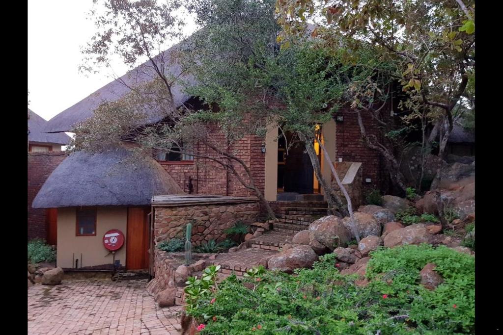 a brick house with a stone stairs leading to a door at Gecko Lodge and Cottage, Mabalingwe in Warmbaths