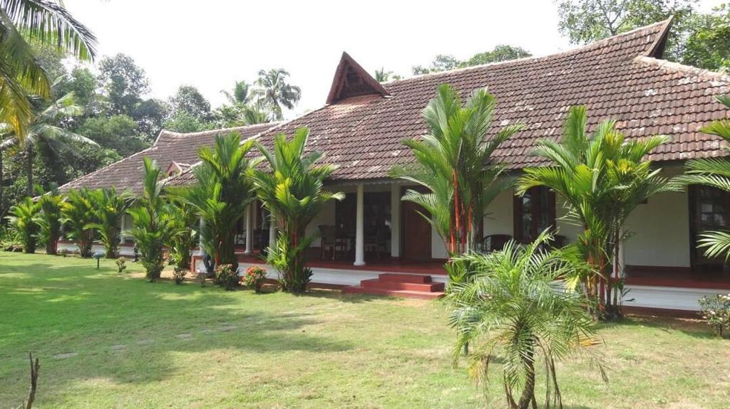 a house with palm trees in front of it at Kovilakam Lakeside Villa in Alleppey