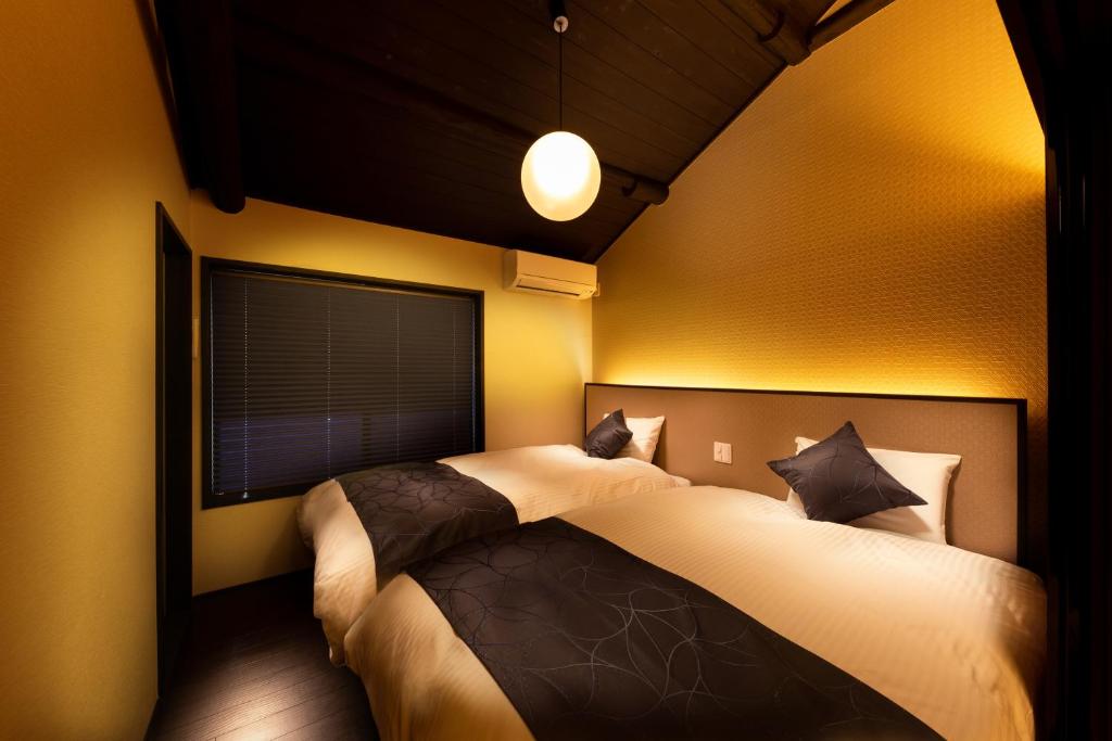 two beds in a bedroom with yellow walls at Tsumugi Kiyomizugojo in Kyoto