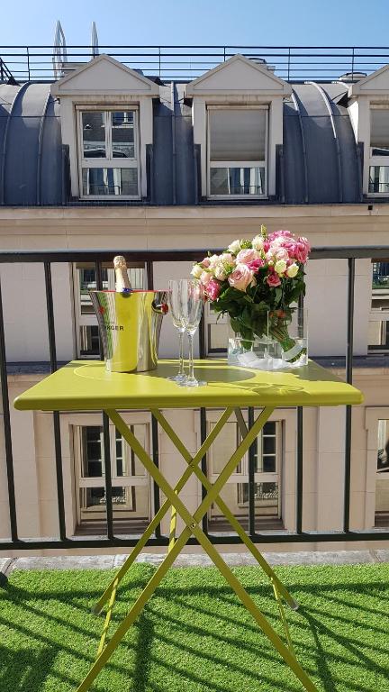 巴黎Lyric Hotel Paris Opera的阳台上的黄色桌子上摆放着鲜花和玻璃杯