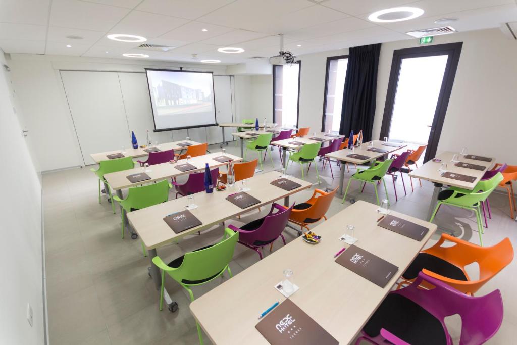 una classe con tavoli, sedie e schermo di proiezione di Nex Hôtel a Tarbes