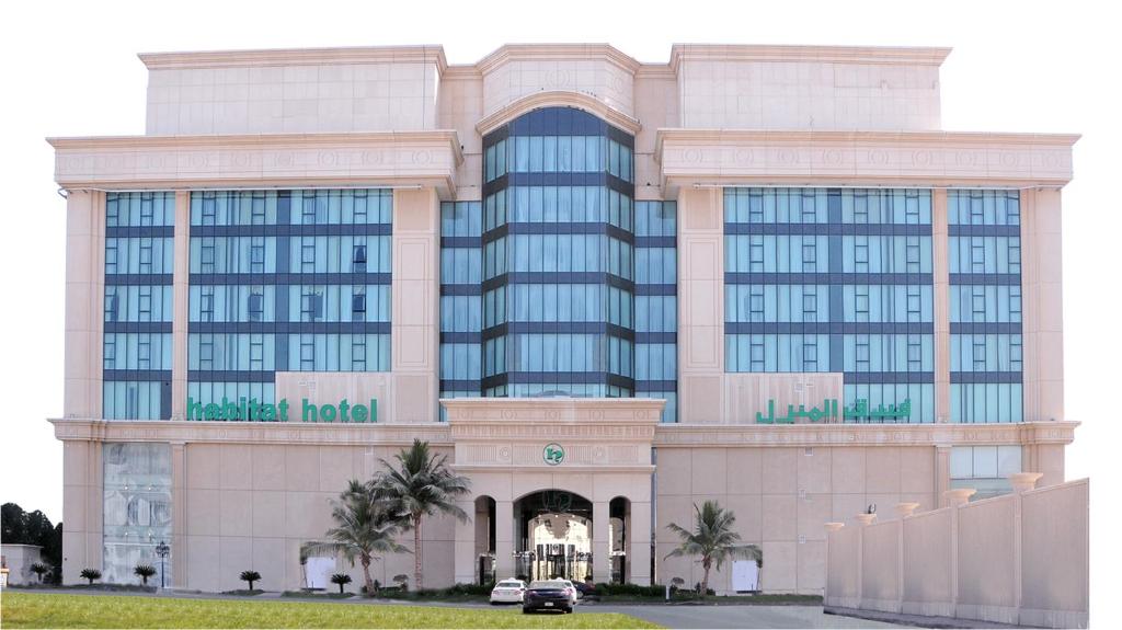 a large building with palm trees in front of it at Habitat Hotel All Suites - Jeddah in Jeddah