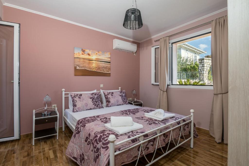 a bedroom with a bed with pink walls and a window at Sofia's apartments in Razáta