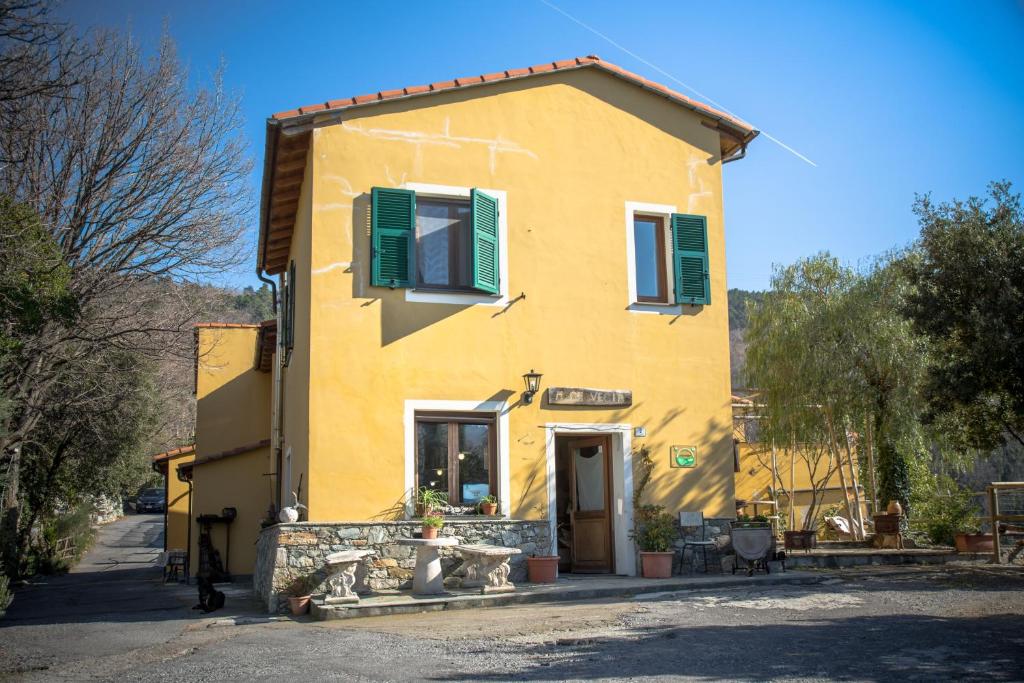 una casa amarilla con persianas verdes en una calle en Agriturismo A Cà Vegia, en Calice Ligure