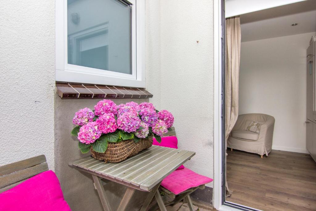 un panier de fleurs roses assises sur une table dans l'établissement Romana, à Zandvoort