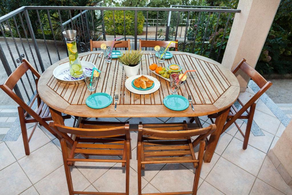 a wooden table with plates of food on a balcony at Apartment Villa Lidija in Lovran