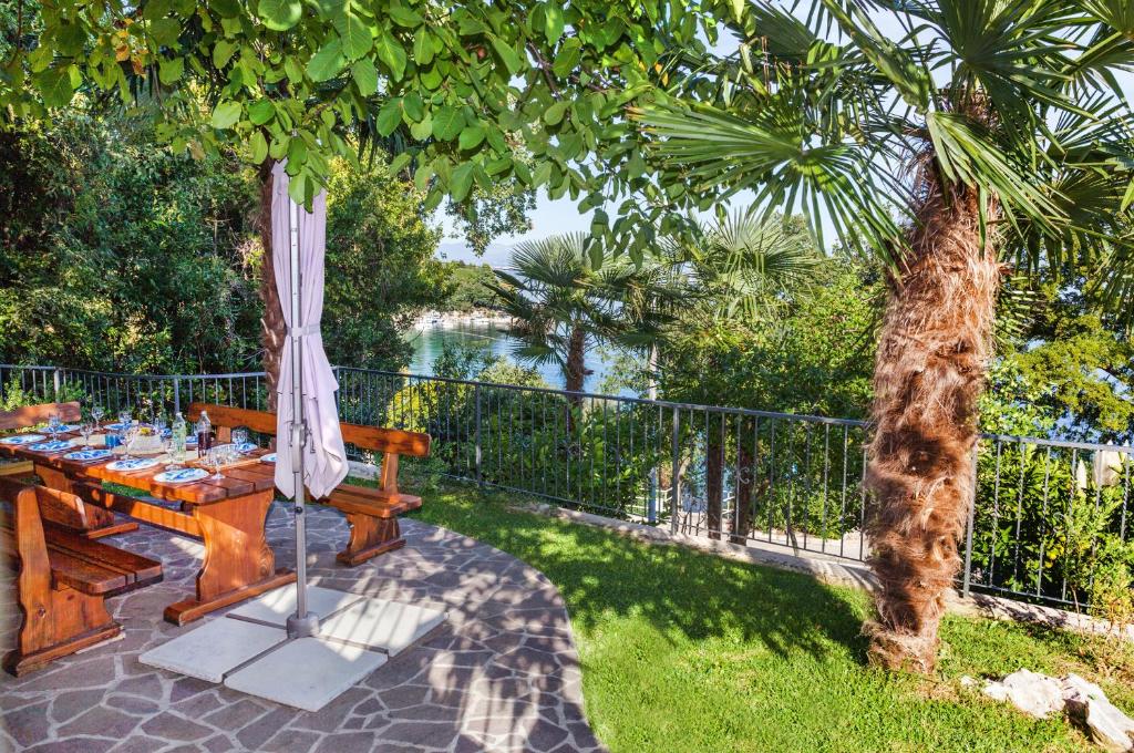 een picknicktafel met een parasol en uitzicht op het water bij Apartment Villa Lidija in Lovran