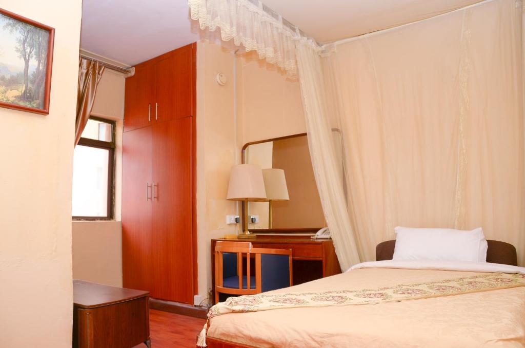 a hotel room with a bed and a desk at Fang Fang Hotel in Kampala
