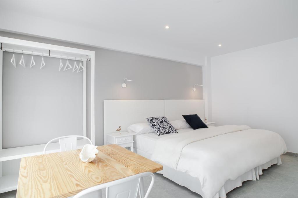 a white bedroom with a bed and a table at INNER Kompas Palmanova "Adults Only" in Palmanova