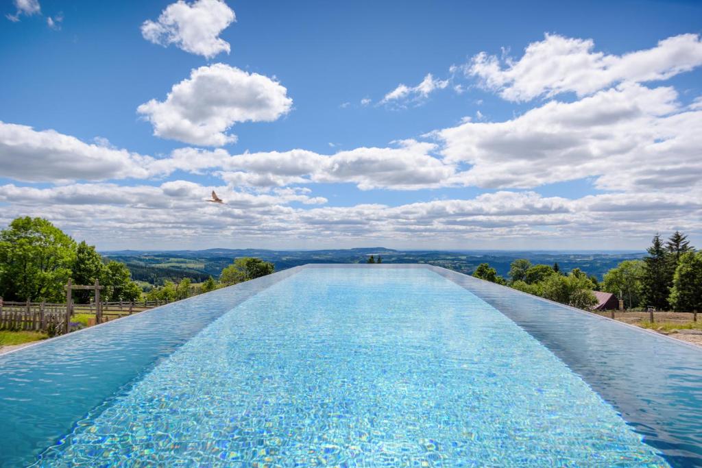 a large swimming pool with a blue sky and clouds at Wellness hotel V Nebi in Kořenov