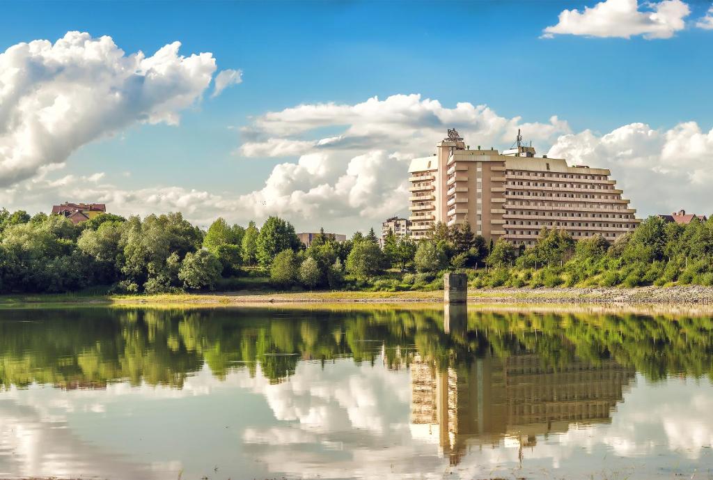 un reflet d'un bâtiment dans une masse d'eau dans l'établissement Resort Hotel Karpaty, à Trouskavets