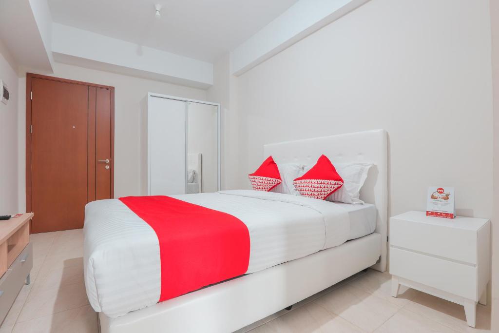 ein weißes Schlafzimmer mit einem roten und weißen Bett in der Unterkunft OYO 498 Green Lake View Ciputat in Pondokcabe Hilir
