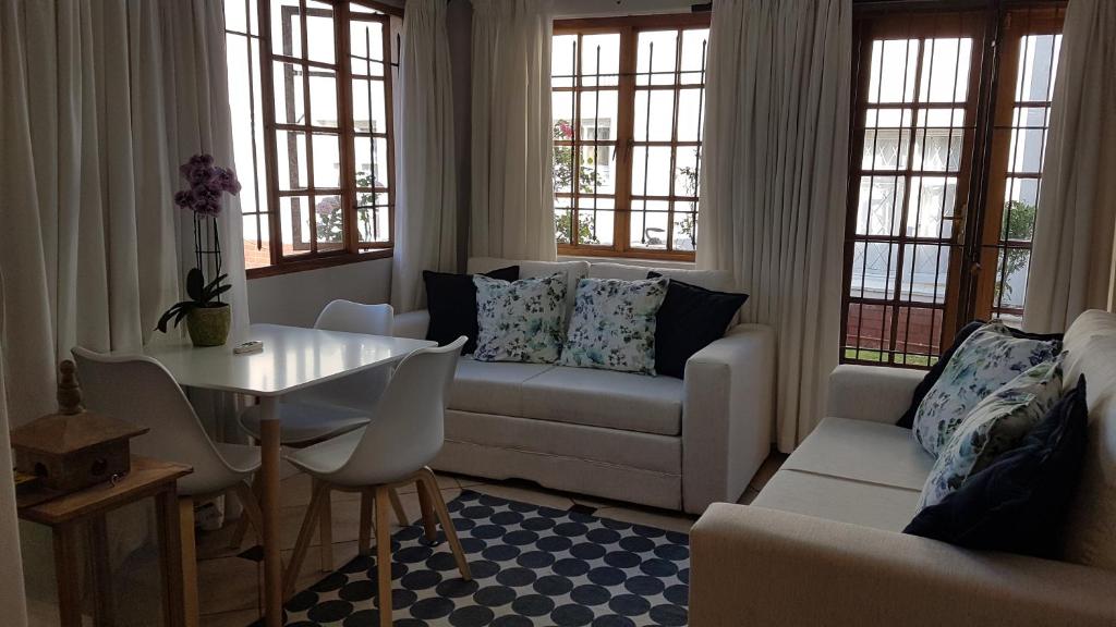 a living room with a couch and a table and windows at Innes Road Durban Accommodation 2 bedroom private unit in Durban