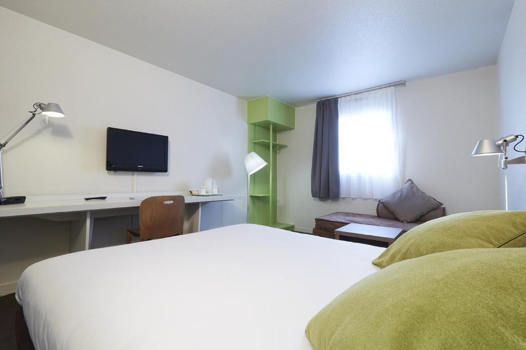 Habitación de hotel con cama, escritorio y TV. en Campanile Blanc-Mesnil en Le Blanc-Mesnil