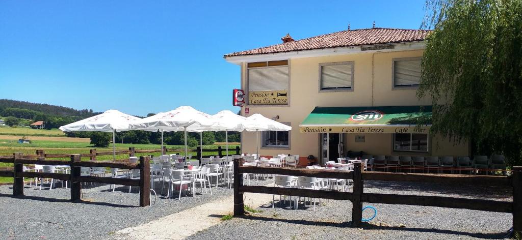 un restaurante con mesas y sombrillas frente a un edificio en Casa Tia Teresa, en Salceda