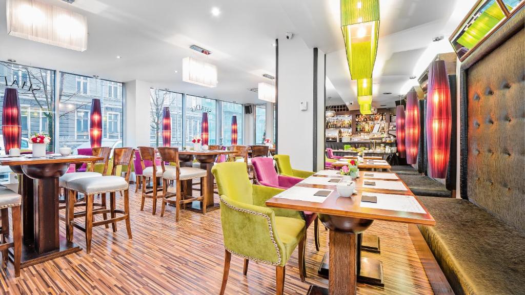 ein Restaurant mit Holztischen und bunten Stühlen in der Unterkunft Don Prestige Residence in Posen