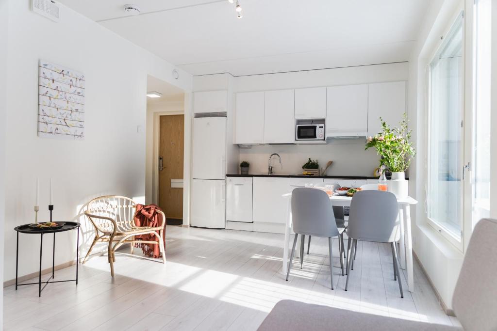 a kitchen with white cabinets and a table and chairs at Spot Apartments Espoo Center in Espoo