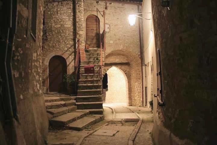 un callejón con escaleras en un edificio antiguo por la noche en Le Case dell'Arco – Monte San Vito, en Scheggino