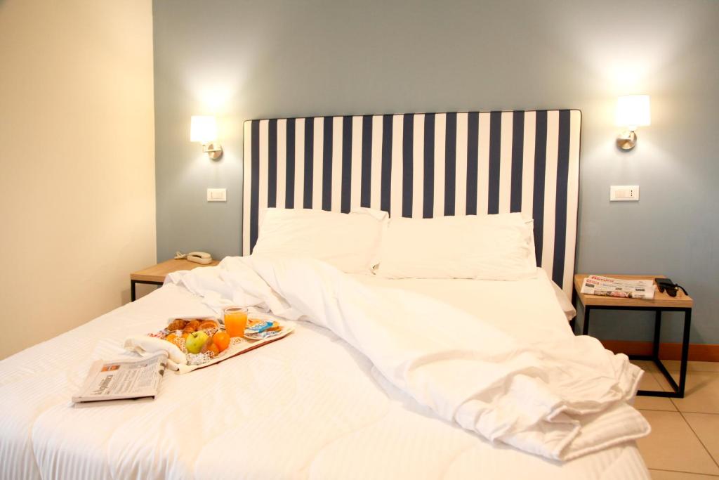 Una cama blanca con una bandeja de comida. en Hotel Majorca sul Mare in centro a Riccione, en Riccione