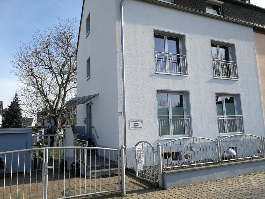 Ein weißes Gebäude mit einem Zaun davor. in der Unterkunft Ferienvilla Koblenz in Koblenz