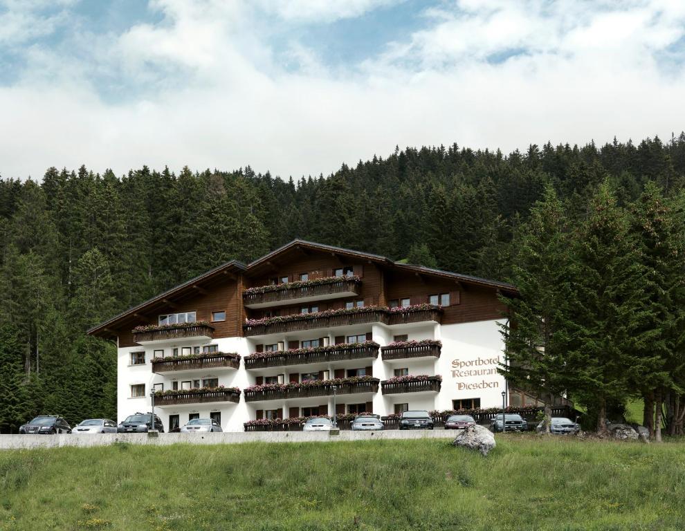 ein großes Apartmenthaus mit Autos auf einem Feld in der Unterkunft Hotel Dieschen in Lenzerheide