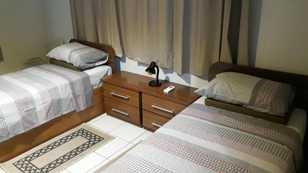 um pequeno quarto com 2 camas e uma cómoda em Edificio Belio em Cascavel