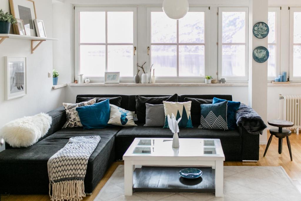 a living room with a black couch with blue pillows at Hallstatt Lake View House in Hallstatt