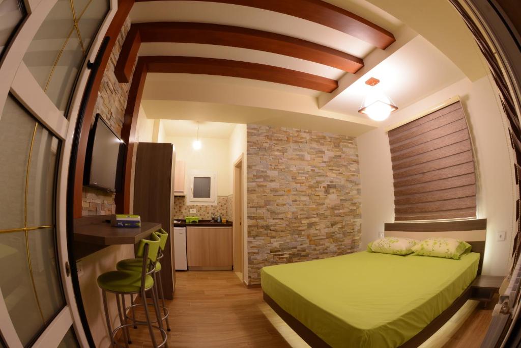 Un dormitorio con una cama verde y una pared de ladrillo en Bauhaus Chalets Apartment, en Bisharri