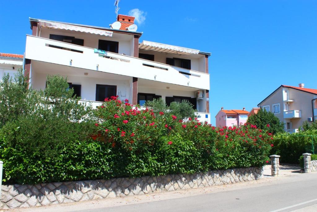 un edificio bianco con fiori rossi di fronte a una strada di Apartment Arna a Krk