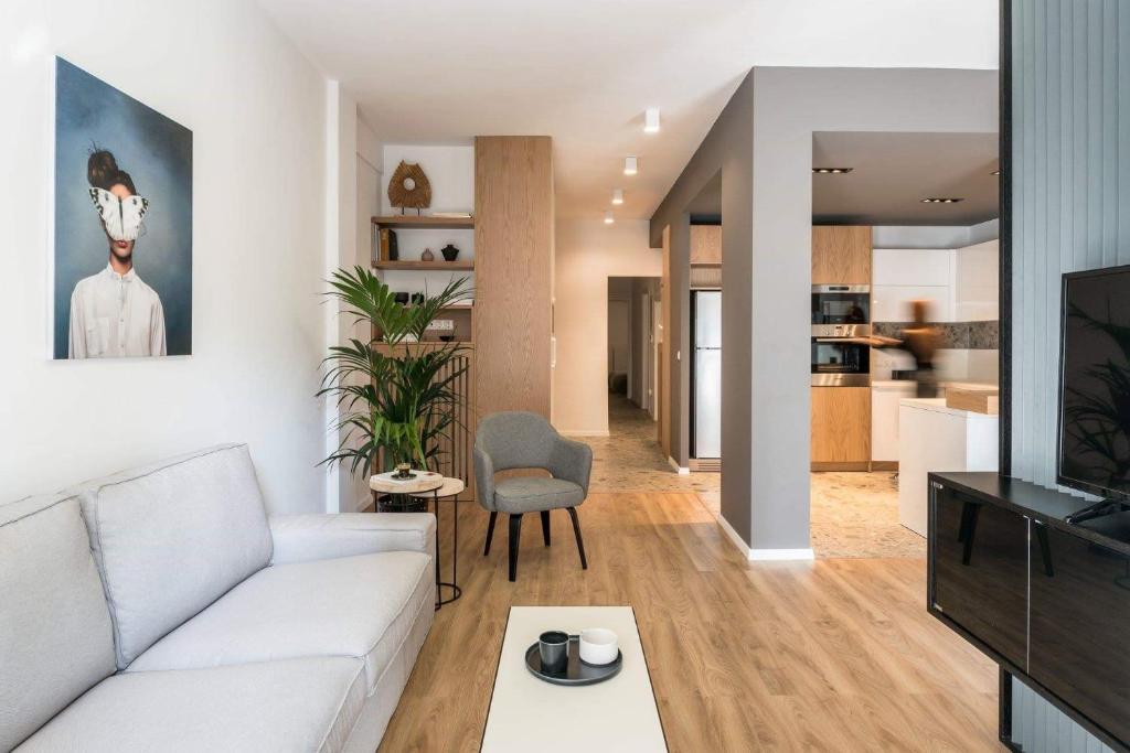 Central C&P Minimal Apartment في سلانيك: غرفة معيشة مع أريكة بيضاء وتلفزيون