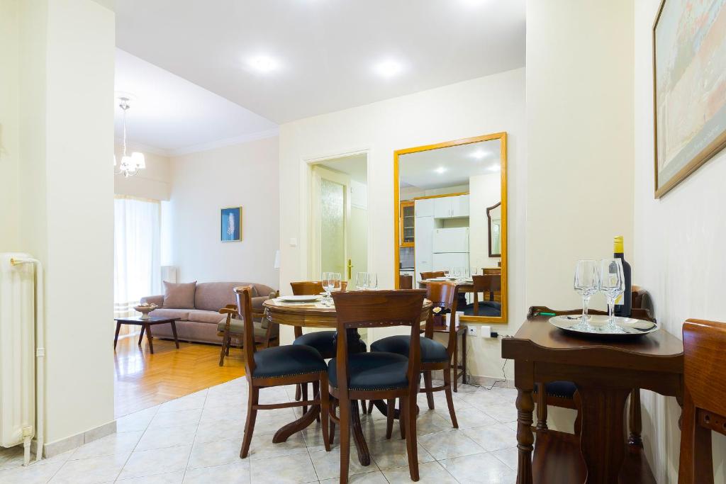 uma sala de jantar com uma mesa, cadeiras e um espelho em Classy 2 bedroom apartment near Acropolis & Metro em Atenas