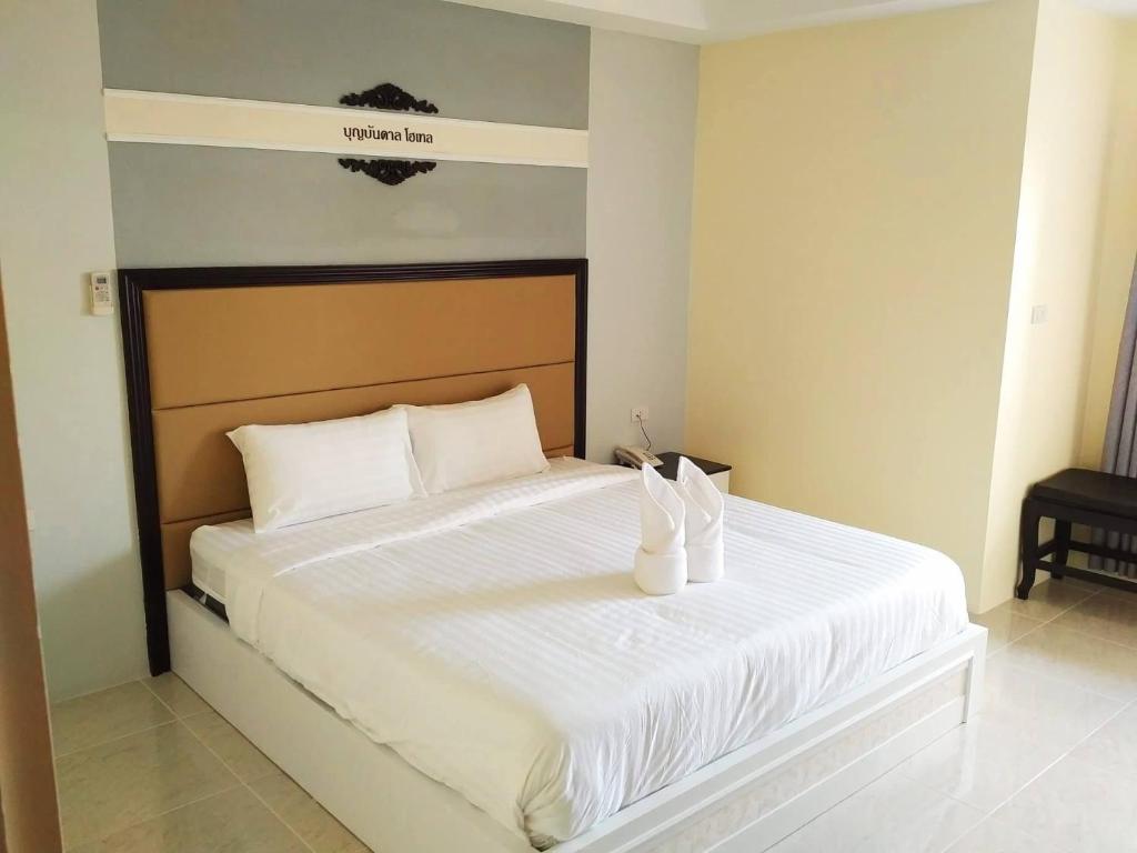 a bedroom with a white bed with two white shoes on it at Boonbundal Hotel in Roi Et