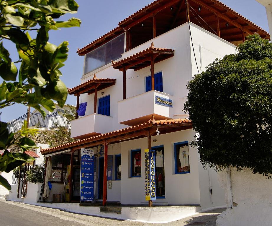 a white building with blue windows on a street at Idroussa in Batsi