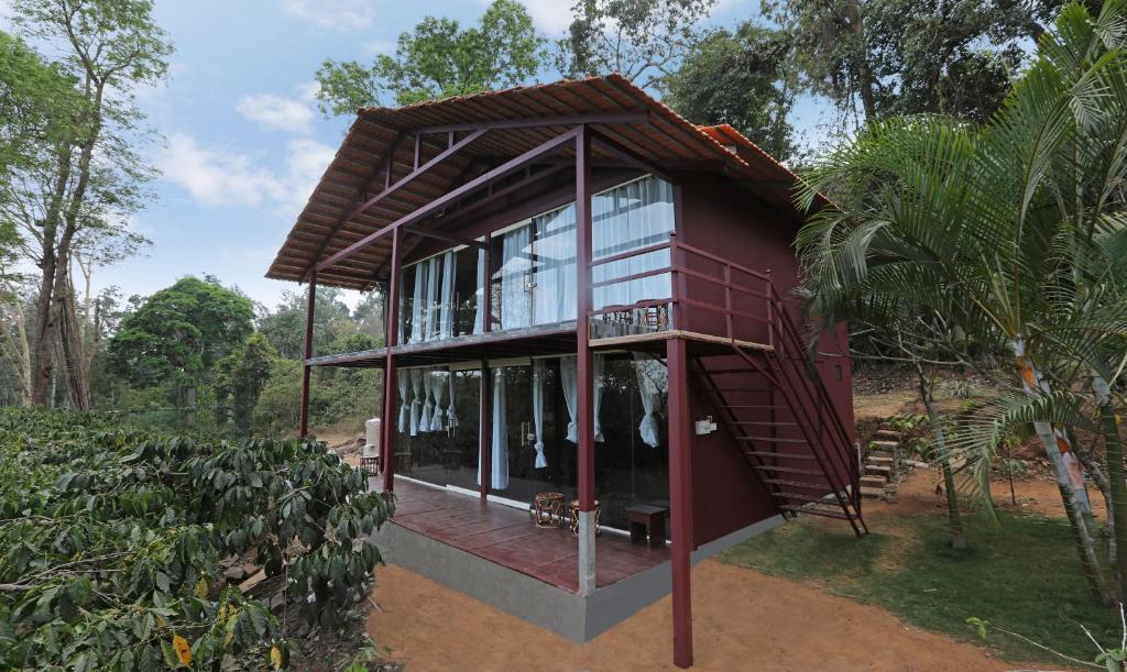a red house with glass windows and a roof at Itsy By Treebo - Jammabane Cottage With Mountain View in Madikeri