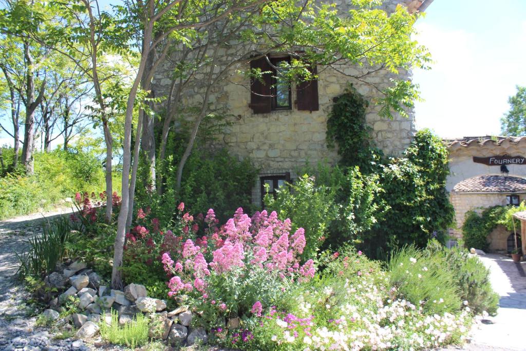 ogród z różowymi kwiatami przed budynkiem w obiekcie Le Mas de Fournery w mieście Villeneuve-de-Berg
