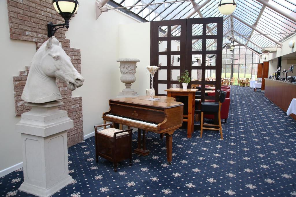 a room with a piano and a horse head on the wall at Hermitage Park Hotel in Coalville