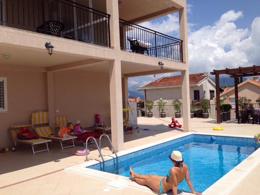 Eine Frau, die am Rande eines Schwimmbads liegt. in der Unterkunft Apartments Villa Viktoria in Tivat